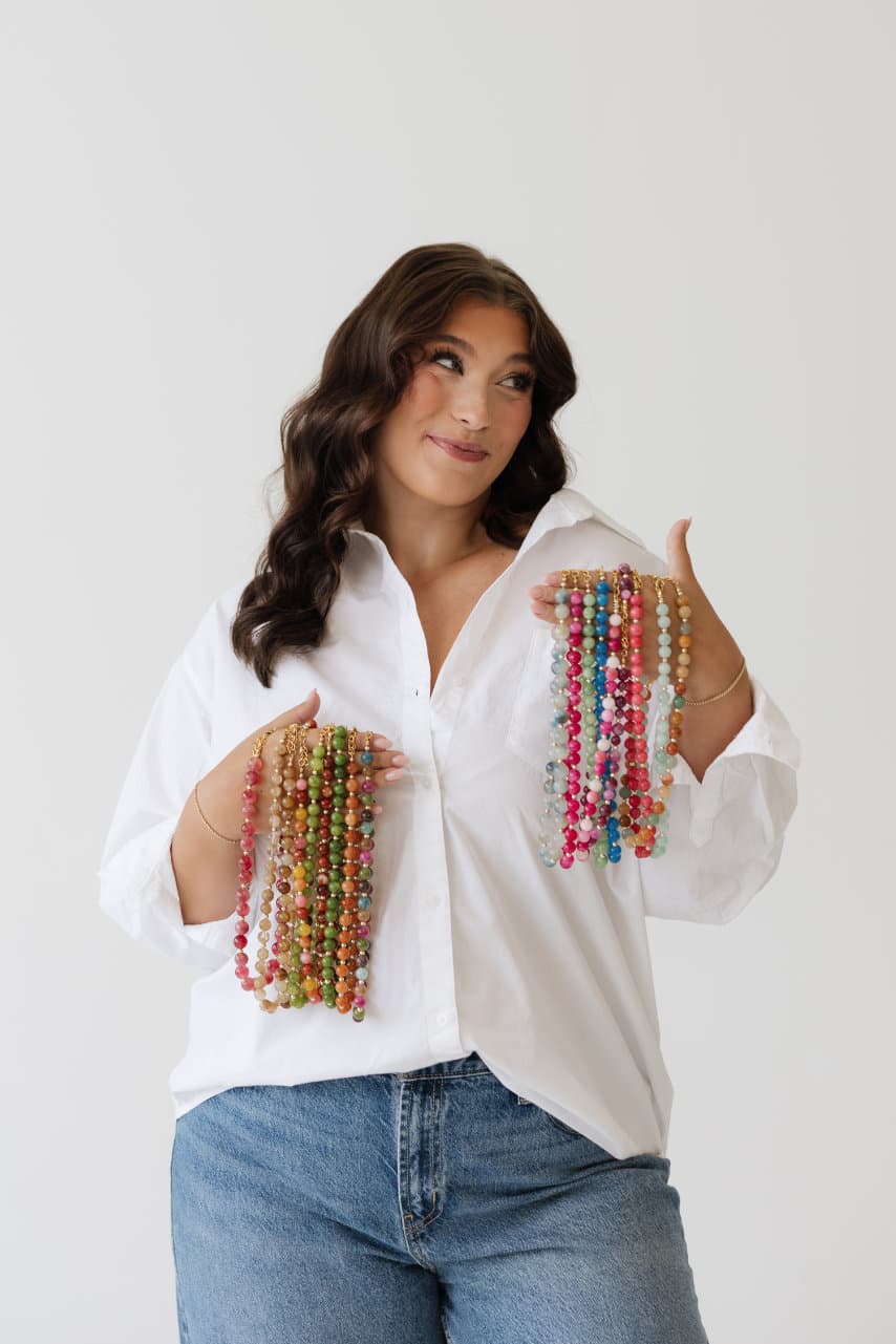 Taylor holding handfuls of beaded necklaces